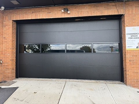 Black flush commercial door with a glass row installed by NJ Garage in Union City, NJ